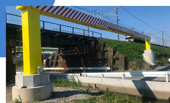 黄色い仮設支柱で支えられた、道路を跨ぐ鉄道橋梁の架設・補修工事の現場風景