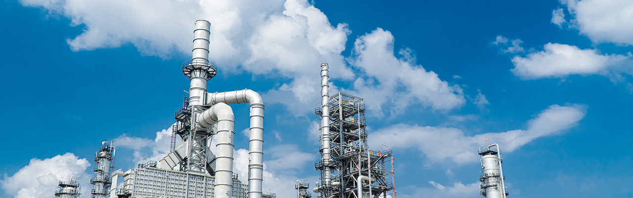 青空に映える、産業プラントの蒸留塔や複雑な配管設備