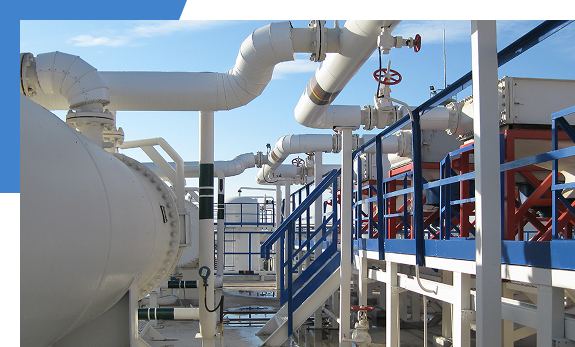 プラントの屋外に設置された、白い断熱材で覆われた複雑な配管