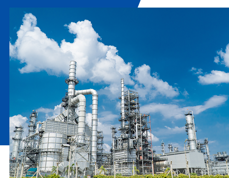 青空を背景に立ち並ぶ産業プラントの蒸留塔と配管設備