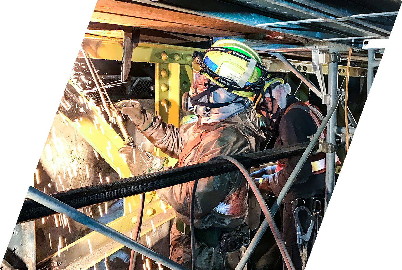 足場内で火花を散らしながら鋼材の溶接を行う技術者