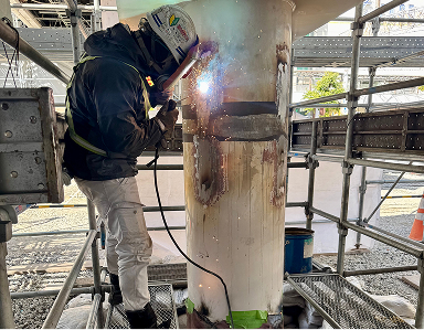 足場上で鋼管の溶接作業を行う技術者