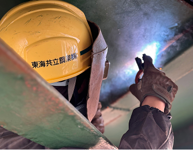 ヘルメットを着用した技術者が狭所で溶接作業を行う様子